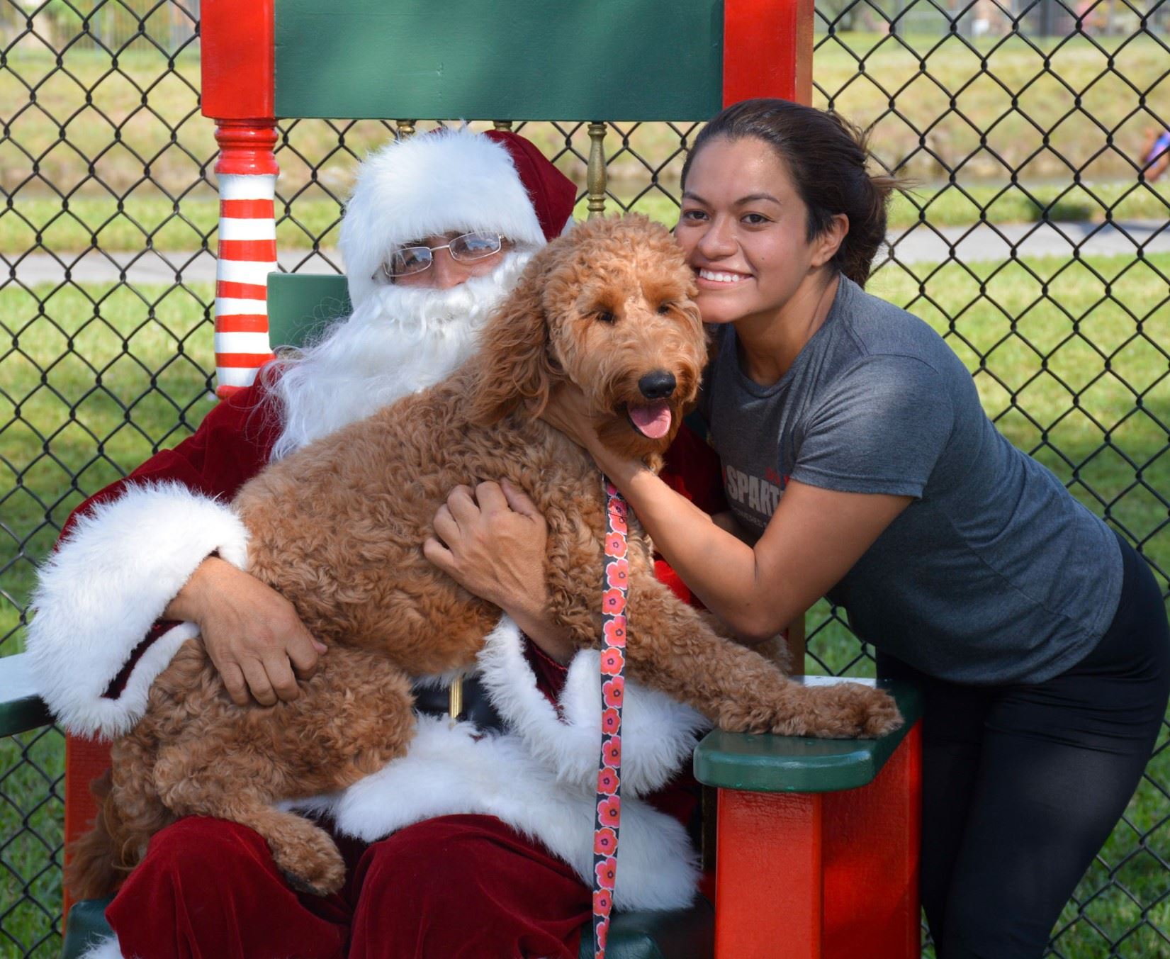 Santa pictured with woman and tan dog.