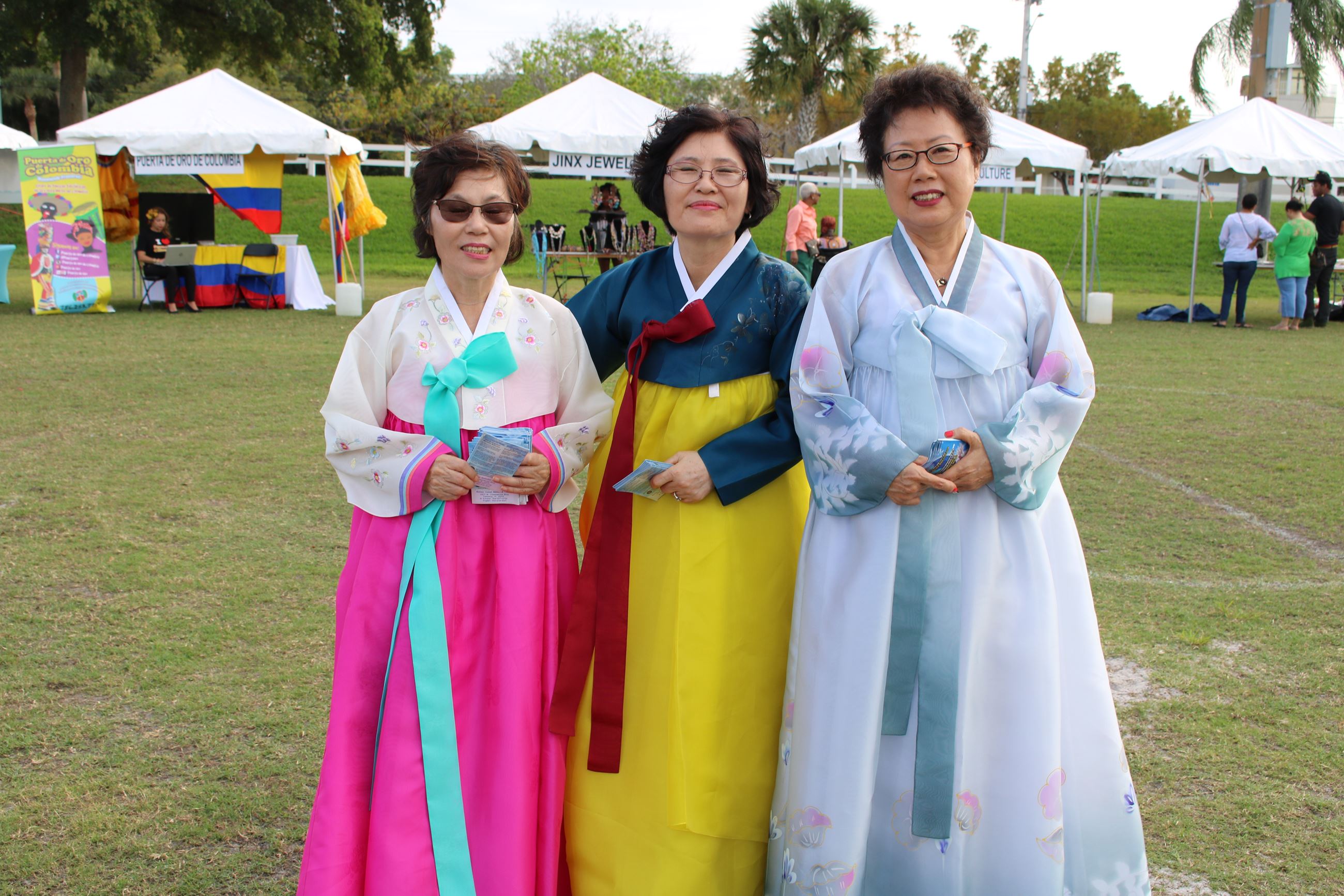 Three individuals dressed in colorful clothing outside in a park 