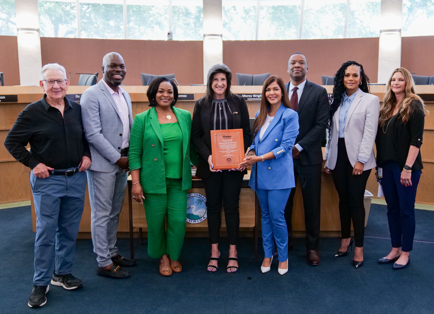 Persons smiling holding a brown plaque